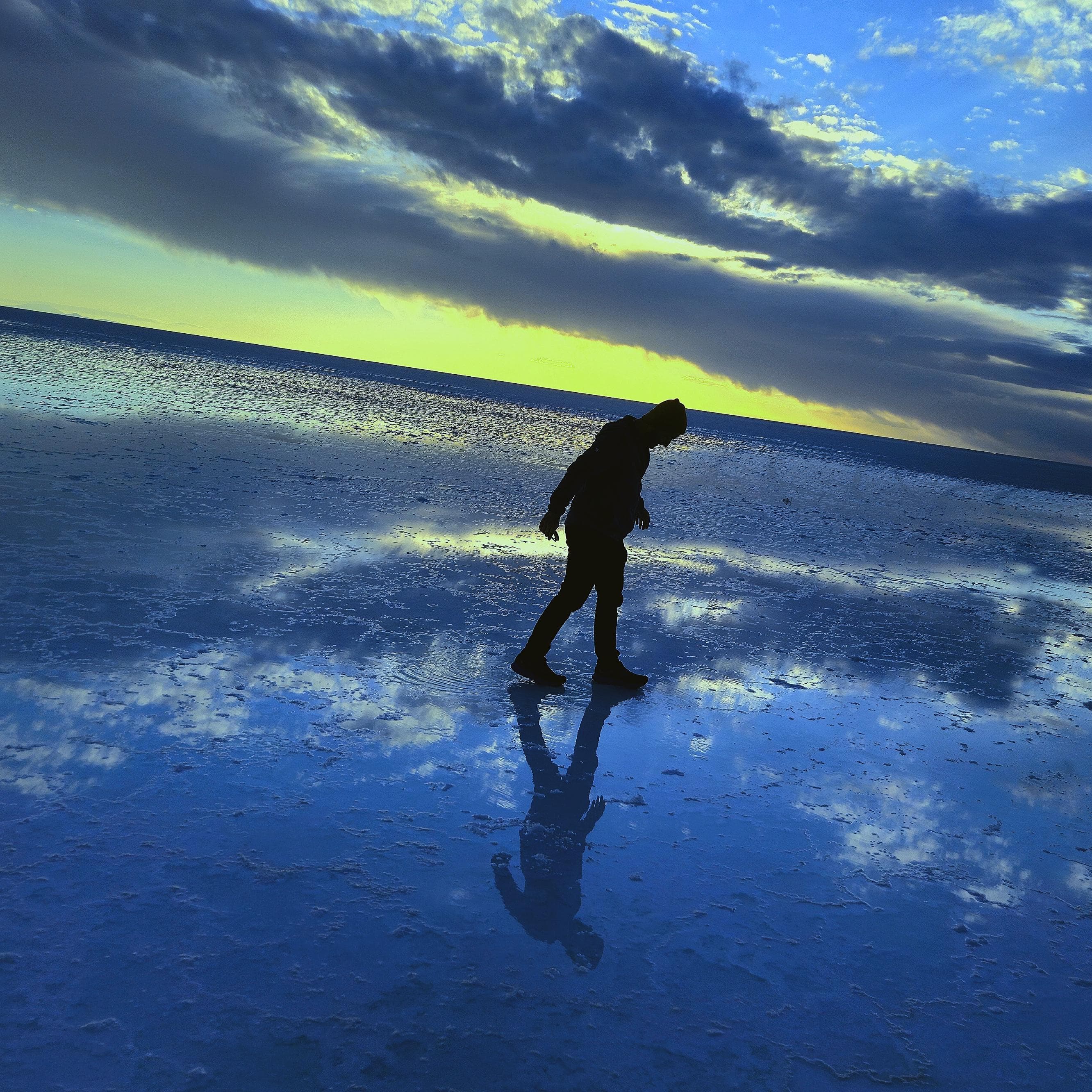 Nathan walking across the reflective Uyuni salt flats at sunset